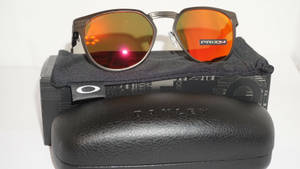 Oakley太陽眼鏡，橙色鏡片，放在品牌眼鏡盒和眼鏡布上。 — 運動 壁紙