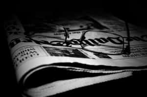 一副放在摺疊報紙上的黑白閱讀眼鏡。 — Old Paper 壁紙