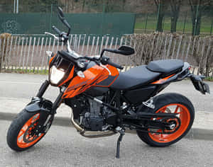 橙色和黑色KTM 390機車停放在圍欄附近的柏油路上 — 巴布風機車 壁紙