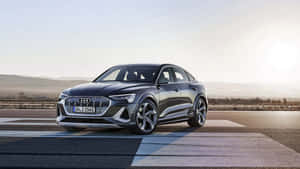 Audi e-tron S電動車在日落時分停在鋪砌道路上，背景有山丘。 — 奧迪 GIF 壁紙