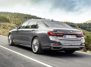 灰色BMW 7系列轎車在森林覆蓋的山丘間的山路上行駛。 — Mercedes Benz C300 壁紙