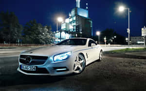 白色Mercedes SLK在夜晚停放在街燈下，靠近一座現代建築。 — 城市 壁紙