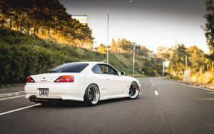 日落時分，白色日產Silvia S15跑車行駛在蜿蜒的道路上。 — 日產 壁紙