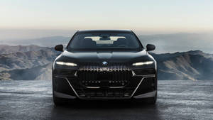 黑色BMW i7電動轎車停在懸崖上，俯瞰黎明的山脈。 — Mercedes Benz C300 壁紙