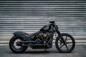 黑色Harley-Davidson機車，金色細節，停放在金屬車庫門前。 — 機車 壁紙