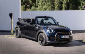 黑色電動MINI Cooper敞篷車在瀝青車道上連接到充電器。 — 1280x800 壁紙
