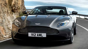 黑色Aston Martin在岩石峭壁的山路上疾馳。 — 奧斯頓馬丁 壁紙