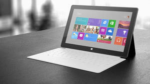 深色桌上的白色Microsoft Surface平板電腦與鍵盤保護蓋。