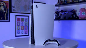 白色PlayStation 5主機和控制器在桌上，配有藍色燈光和普普藝術海報。 — PS5 動態圖片 壁紙