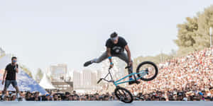 BMX車手在日間活動中，於歡呼的人群前表演特技。 — 攀爬 壁紙