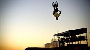 BMX車手在日落活動中空中翻騰，觀眾觀看 — X Games 壁紙