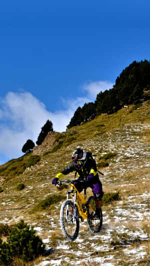 山地自行車手騎著亮黃色自行車從積雪的草坡上滑下。 — 登山車 壁紙