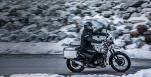 摩托車手騎著銀色探險摩托車穿越積雪的山脈。
