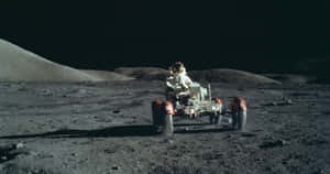 太空人駕駛月球車，在黑色天空下行駛在月球灰色表面上。 — NASA 動態圖片 壁紙