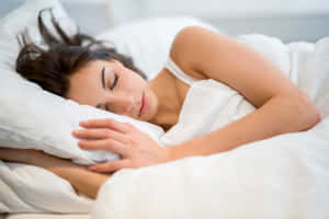 一名女子在白色床單和枕頭的床上熟睡。 — 睡眠 壁紙