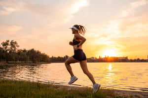 女子在金色日落時於湖岸慢跑 — Running 壁紙