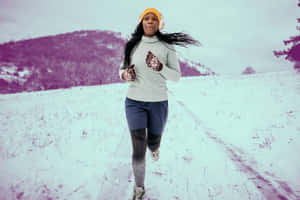 一名女子在雪中慢跑，身後有紫色山脈。 — 寒冷 壁紙