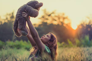 女子在金色夕陽田野中高舉泰迪熊 — 可愛熊 壁紙