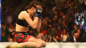 女性MMA拳手在八角籠內跪著遮臉。 — 勝利 壁紙