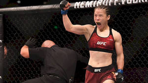 女性MMA拳手在UFC八角籠中高舉拳頭慶祝勝利。 — 運動 壁紙