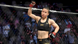 女性MMA拳手在UFC八角籠中高舉拳頭慶祝勝利。 — 運動 壁紙