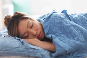 一名女性在床上蓋著藍色被子熟睡。 — 睡眠 壁紙