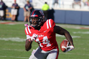 美式足球員在草地上持球奔跑 — Dk Metcalf 壁紙