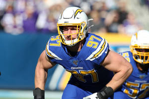 身穿Chargers球衣的NFL足球運動員在比賽期間在場上奔跑。 — 運動 壁紙