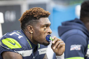 美式足球員在練習時穿著海鷹隊球衣喝水。 — Dk Metcalf 壁紙