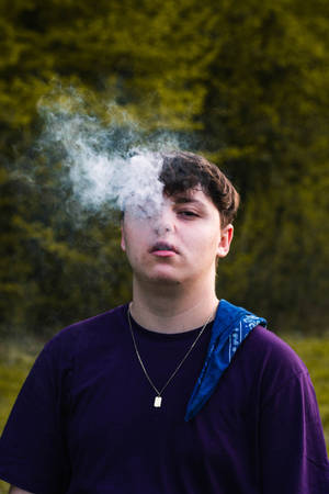 青少年在戶外呼出煙霧，背景是森林。 — 抽菸 壁紙