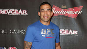 身穿藍色UFC T恤的男子在活動中微笑，身後有Budweiser和RevGear標誌。 — 運動 壁紙