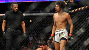 MMA戰士在八角籠中站在被擊敗的對手上方，裁判在附近。 — 終極格鬥冠軍賽 壁紙