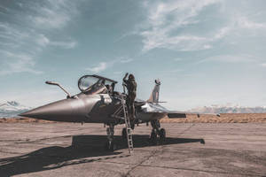 飛行員在停機坪上登上戰鬥機，背景有雪山 — 空軍 壁紙
