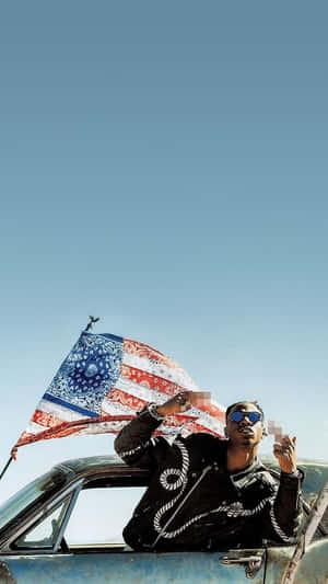戴太陽眼鏡的男子從車窗探出身子，在沙漠中揮舞美國國旗。 — 嘻哈 壁紙