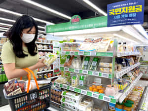 戴口罩女性在韓國超市通道選購蔬菜。 — 7-ELEVEN 壁紙