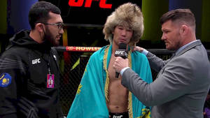 戴著皮草帽、身穿青綠色長袍的UFC拳手在八角籠內接受訪問。 — 運動 壁紙
