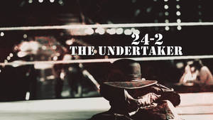 戴黑色帽子和外套的摔角手坐在擂台上，帶有文字24-2 THE UNDERTAKER。 — 送葬者 壁紙