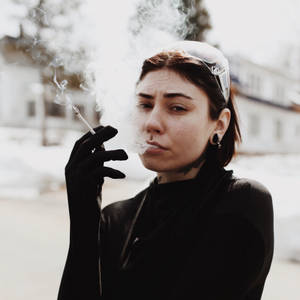 戴黑色手套的女性在雪景都市環境中戶外吸煙。 — 抽菸 壁紙