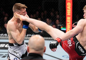 MMA拳手在八角籠中向對手面部踢出高踢 — 運動 壁紙