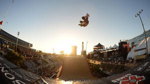 X Games日落活動中，滑板手在半空中，人群歡呼。 — X Games 壁紙