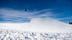 滑雪板運動員在明亮的冬日裡騰空於雪坡之上 — X Games 壁紙