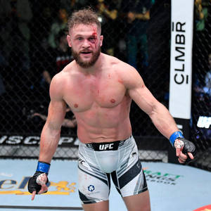 UFC拳手滿臉鮮血，短褲破爛，在八角籠內慶祝勝利。 — 運動 壁紙