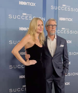 兩名演員在Succession HBO Max活動中，在帶有品牌標誌的藍色牆壁前擺姿勢。 — 小米 Mix Flip 2 壁紙