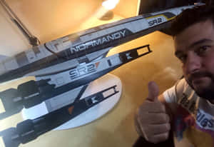 男子在Normandy SR2太空船模型旁邊豎起大拇指。 — 木星 GIF 壁紙