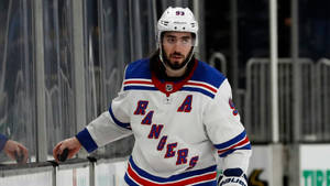 穿著 Rangers 球衣的冰球運動員在比賽中靠在溜冰場玻璃上。 — 運動 壁紙