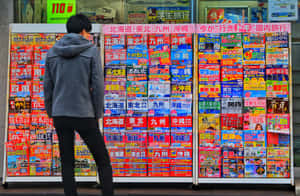 在城市商店櫥窗前瀏覽日本旅遊手冊的人。 — 水果 壁紙