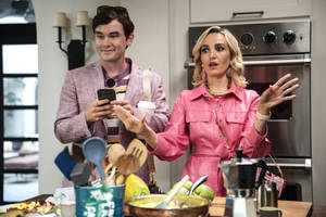 粉紅西裝外套男子查看手機，粉紅皮夾克女子在廚房驚訝反應。 — 新娘的父親 壁紙