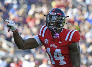 穿著紅色 Ole Miss 14號球衣的美式足球員在比賽中舉起拳頭慶祝。 — Dk Metcalf 壁紙