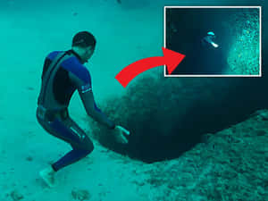 潛水員探索一個有碧綠海水的黑暗水下洞穴。 — 4:3 壁紙
