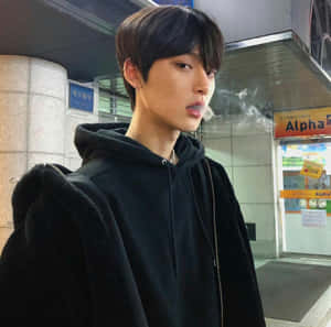 穿著黑色連帽衫的年輕男子在夜晚的都市車站中呼出煙霧。 — 獨立小孩美學 壁紙